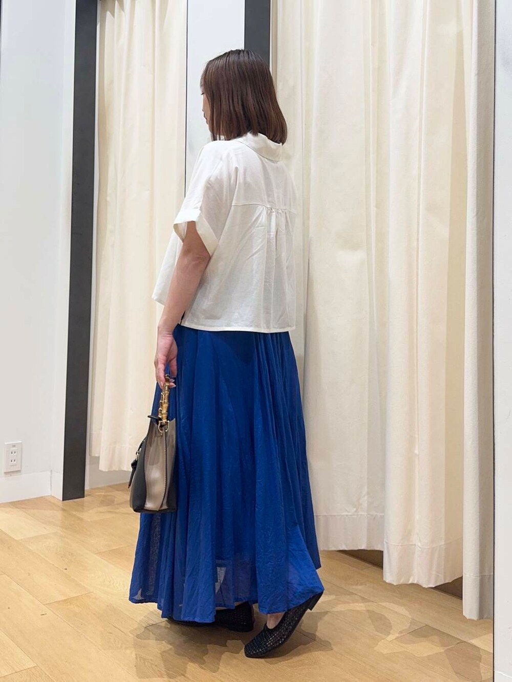 ブラック系のバレエシューズ、ブルー系のスカート、ホワイト系のシャツ/ブラウスを着用したレディースの夏コーディネートの3枚目の写真