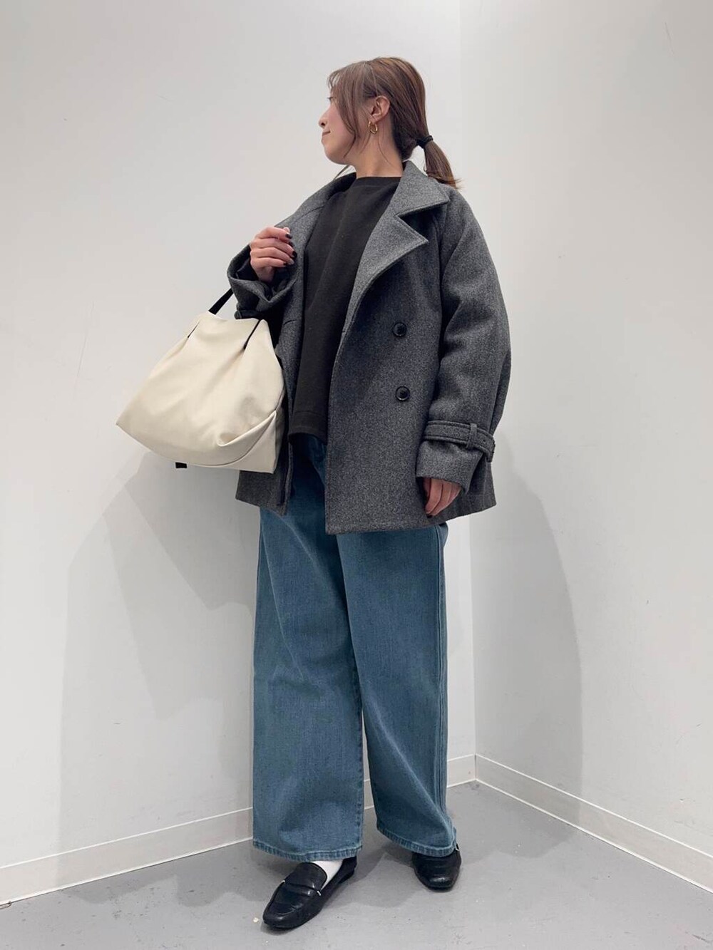 ブラック系のローファー、ホワイト系のショルダーバッグ、グレー系のトレンチコートを着用したレディースの冬コーディネートの4枚目の写真