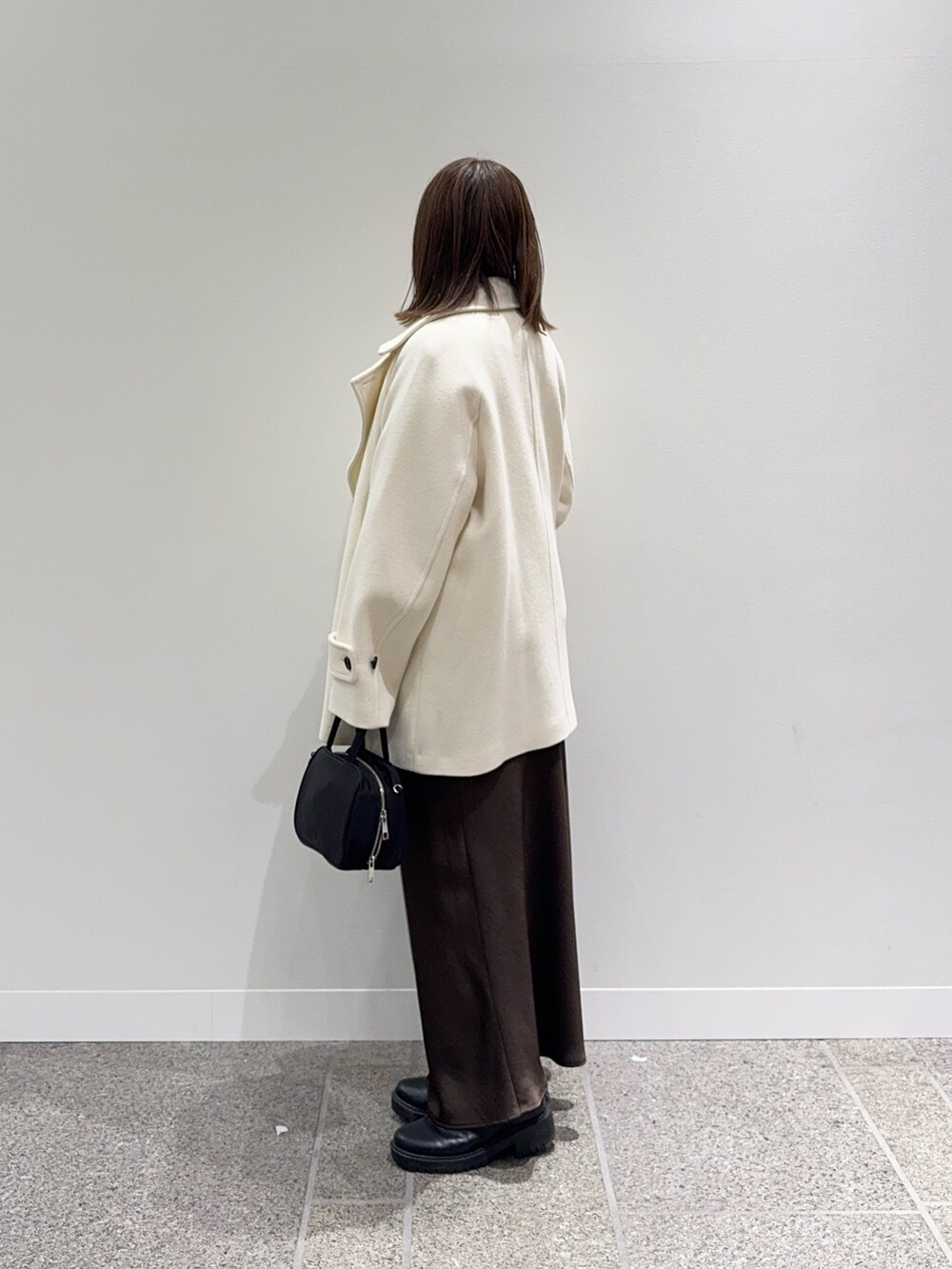 ホワイト系のピーコート、ホワイト系のニット/セーター、ブラック系のボストンバッグを着用したレディースの冬コーディネートの2枚目の写真