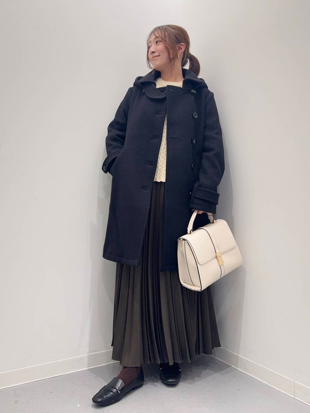 ブラック系のローファー、ブラック系のその他アウター、ホワイト系のハンドバッグを着用したレディースの冬コーディネートの3枚目の写真