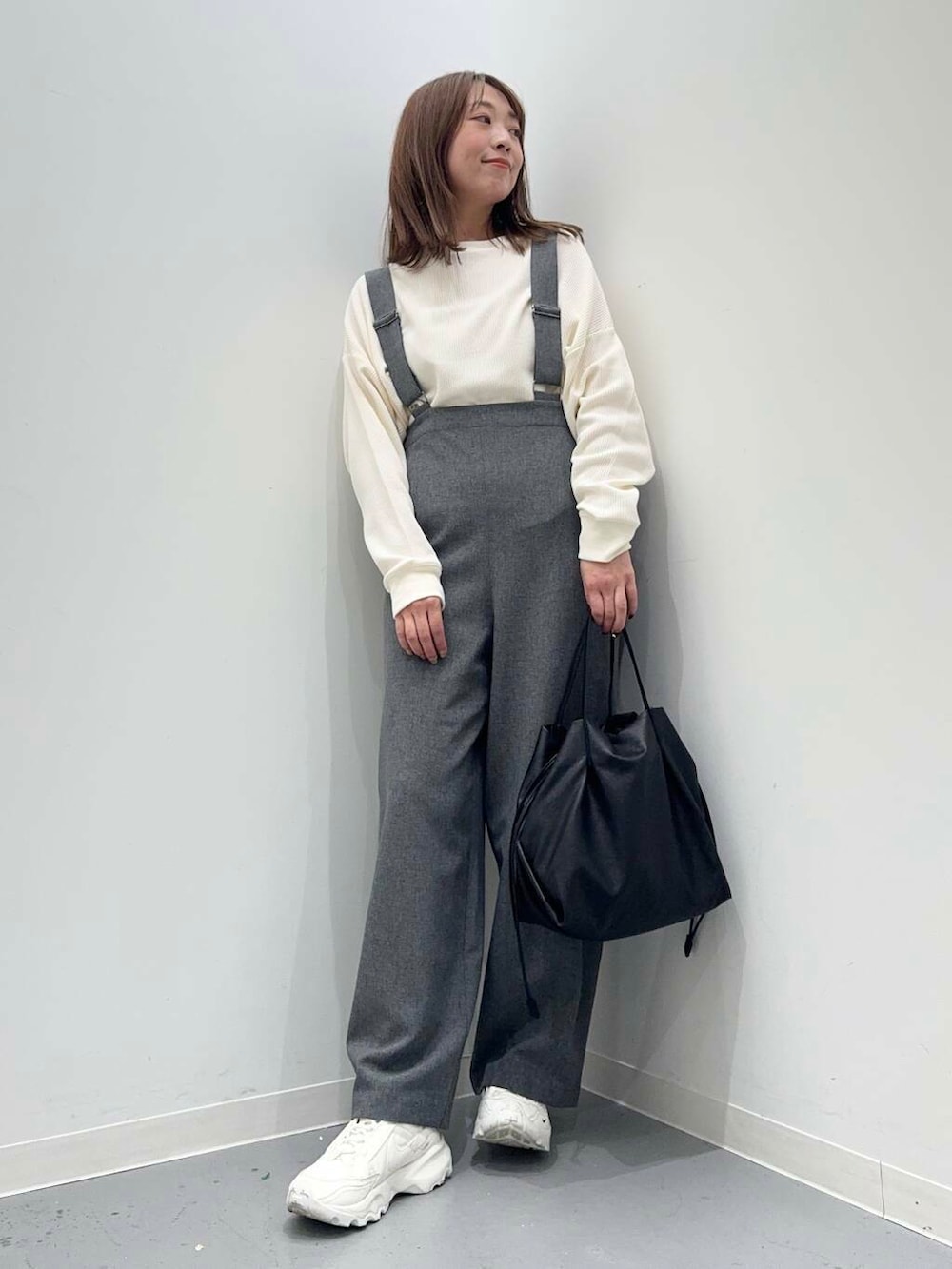ホワイト系のショルダーバッグ、ホワイト系のスニーカー、グレー系のサロペット/オーバーオールを着用したレディースの秋コーディネートの3枚目の写真