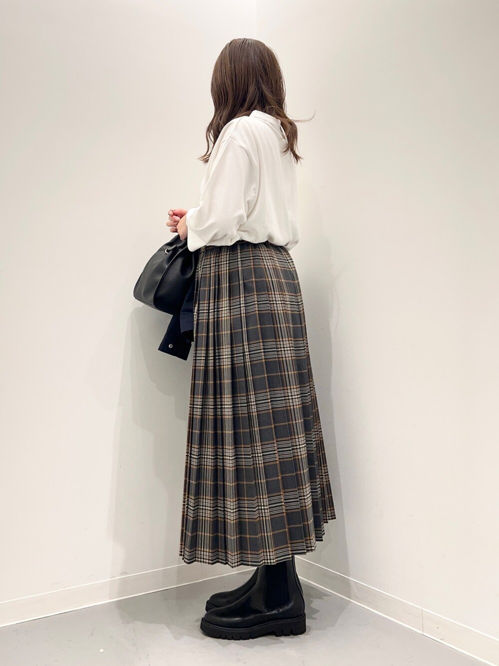 ホワイト系のTシャツ/カットソー、グレー系のスカート、ブルー系のダウンベストを着用したレディースの秋コーディネートの3枚目の写真