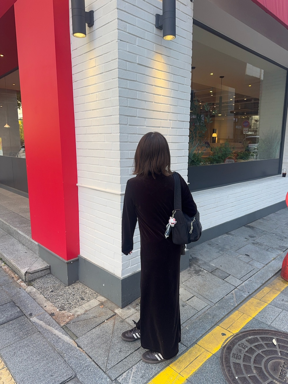 ブラウン系のワンピース、ブラウン系のスニーカー、ブラック系のショルダーバッグを着用したレディースの秋コーディネートの4枚目の写真