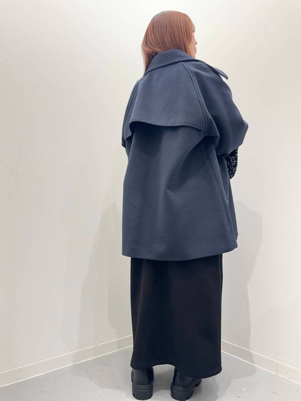 ブラック系のショルダーバッグ、ブラック系のブーツ、ブルー系のステンカラーコートを着用したレディースの冬コーディネートの4枚目の写真