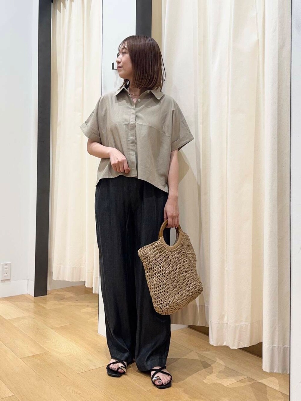 ベージュ系のトートバッグ、ブラック系のデニムパンツ、ブラック系のサンダルを着用したレディースの夏コーディネートの5枚目の写真