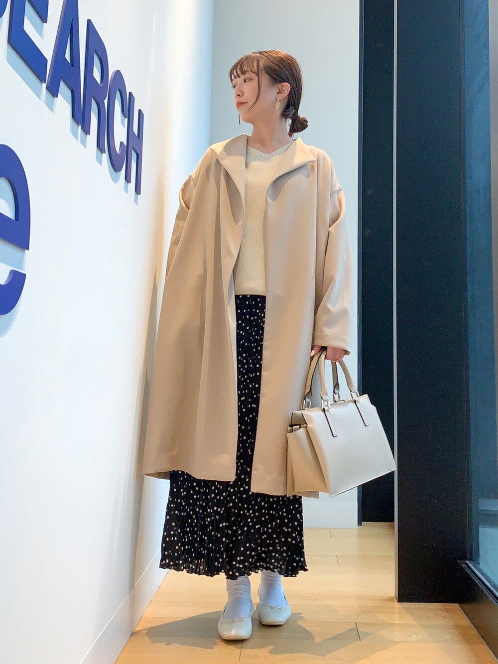 ホワイト系のニット/セーター、ブラック系のスカート、ベージュ系のその他アウターを着用したレディースの春コーディネートの2枚目の写真