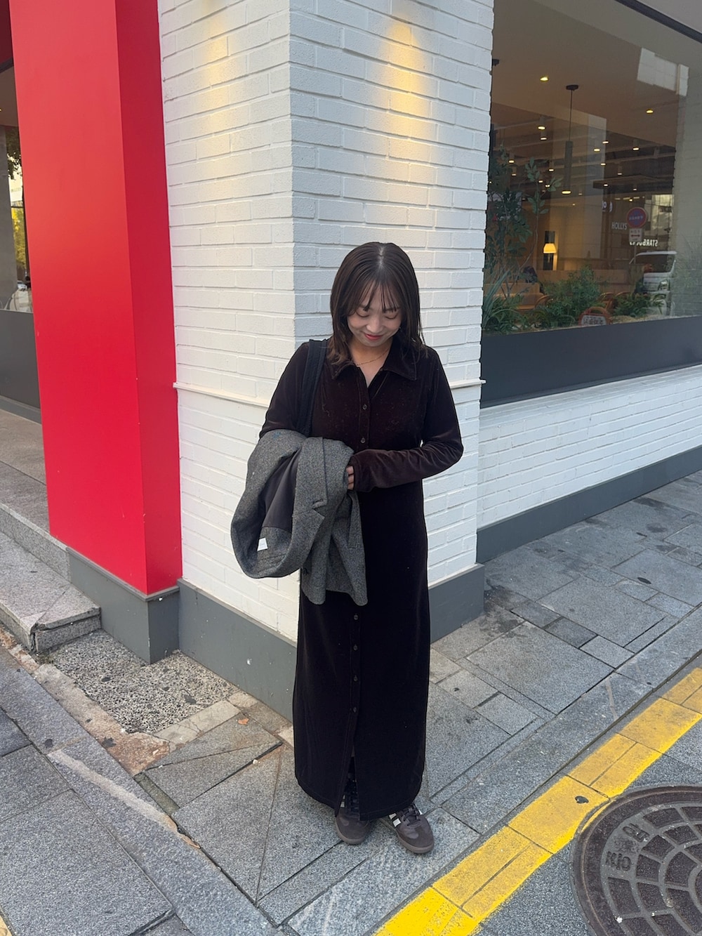 ブラウン系のワンピース、ブラウン系のスニーカー、ブラック系のショルダーバッグを着用したレディースの秋コーディネートの3枚目の写真