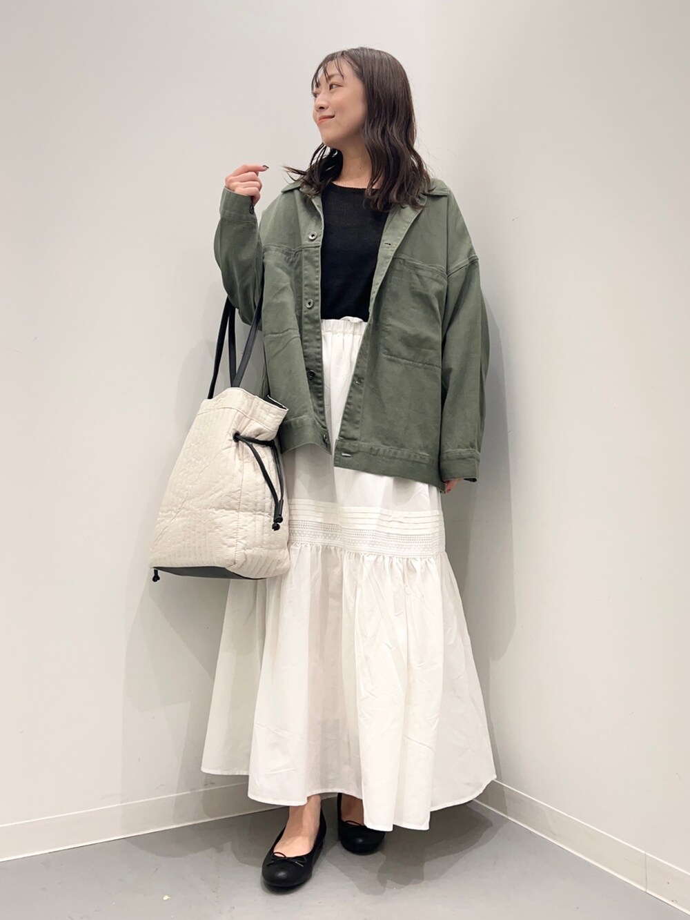 グリーン系のジャケット/アウター、ブラック系のニット/セーター、ホワイト系のスカートを着用したレディースの夏コーディネートの2枚目の写真