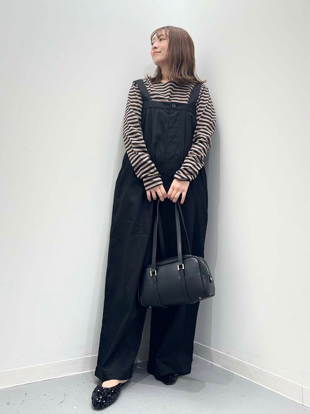 ブラック系のその他シューズ、ブラック系のボストンバッグ、オレンジ系のTシャツ/カットソーを着用したレディースの秋コーディネートの5枚目の写真