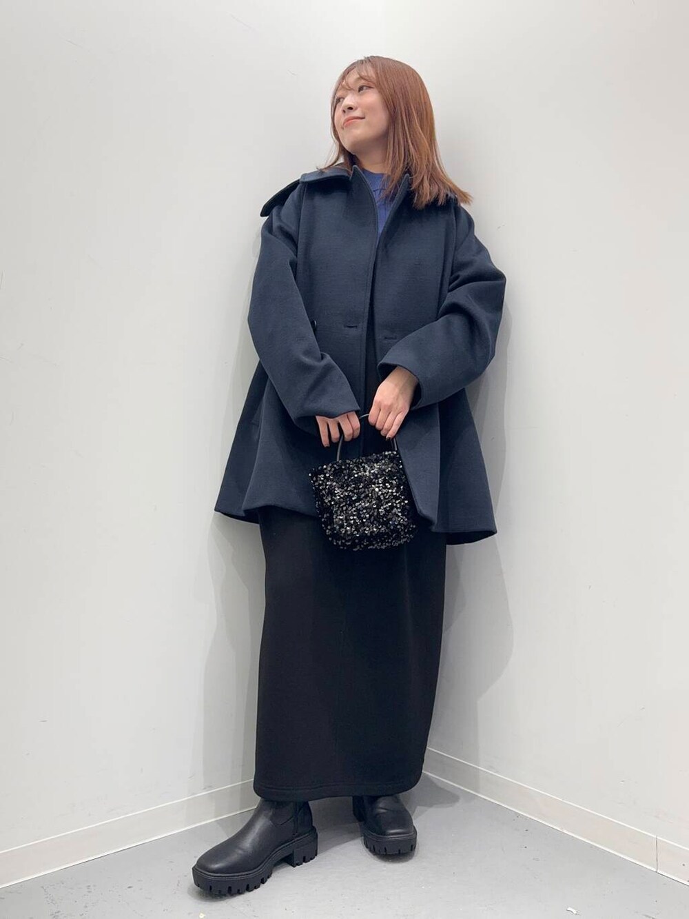ブラック系のショルダーバッグ、ブラック系のブーツ、ブルー系のステンカラーコートを着用したレディースの冬コーディネートの2枚目の写真