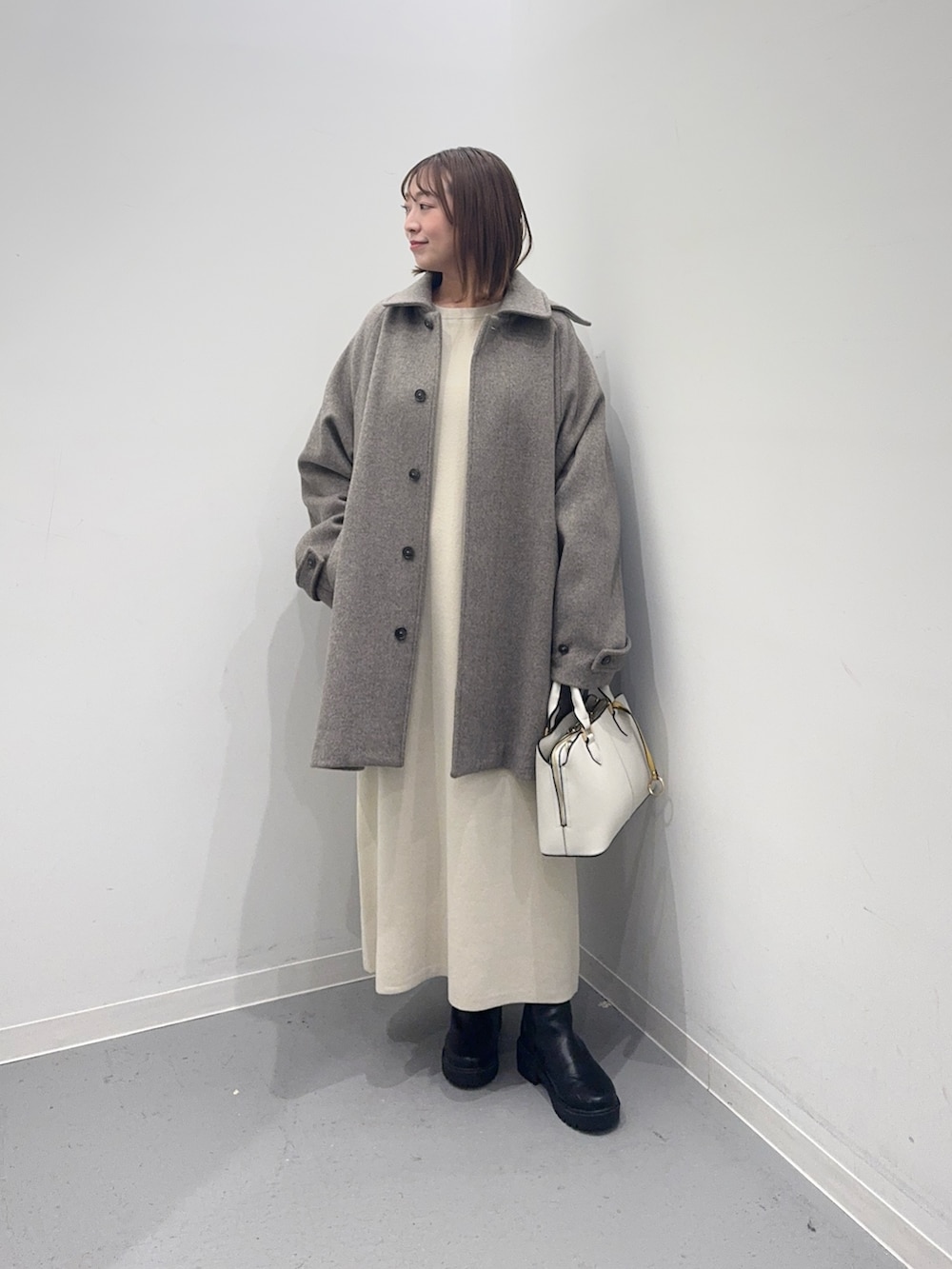 ベージュ系のその他アウター、ベージュ系のワンピース、ホワイト系のハンドバッグを着用したレディースの冬コーディネートの2枚目の写真