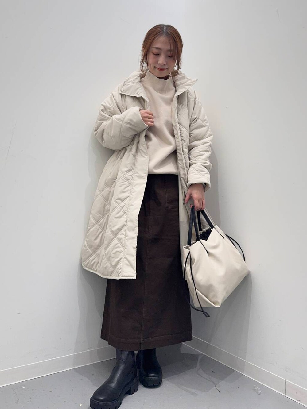 ホワイト系のショルダーバッグ、ブラック系のブーツ、ベージュ系のその他アウターを着用したレディースの冬コーディネートの5枚目の写真