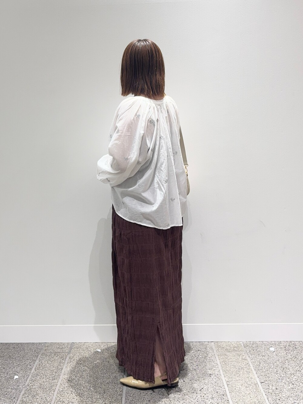 ホワイト系のシャツ/ブラウス、ブラウン系のスカート、ベージュ系のパンプスを着用したレディースの秋コーディネートの4枚目の写真