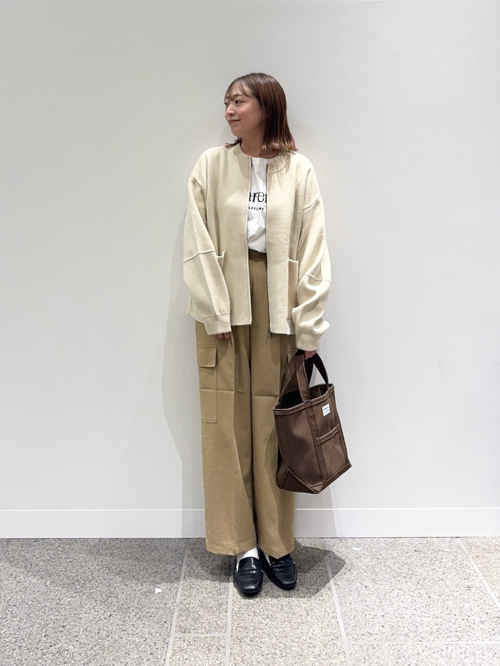 ベージュ系のニット/セーター、ホワイト系のTシャツ/カットソー、ブラウン系のトートバッグを着用したレディースの秋コーディネートの6枚目の写真