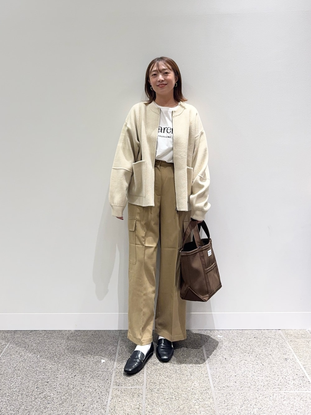 ベージュ系のニット/セーター、ホワイト系のTシャツ/カットソー、ブラウン系のトートバッグを着用したレディースの秋コーディネートの2枚目の写真