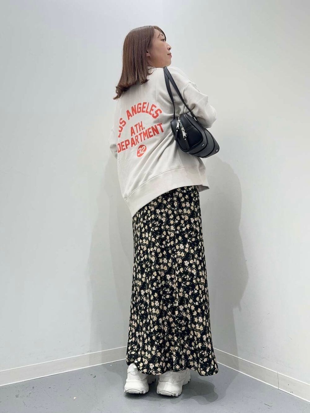 ホワイト系のスニーカー、ブラック系のボストンバッグ、ブラック系のスカートを着用したレディースの秋コーディネートの3枚目の写真