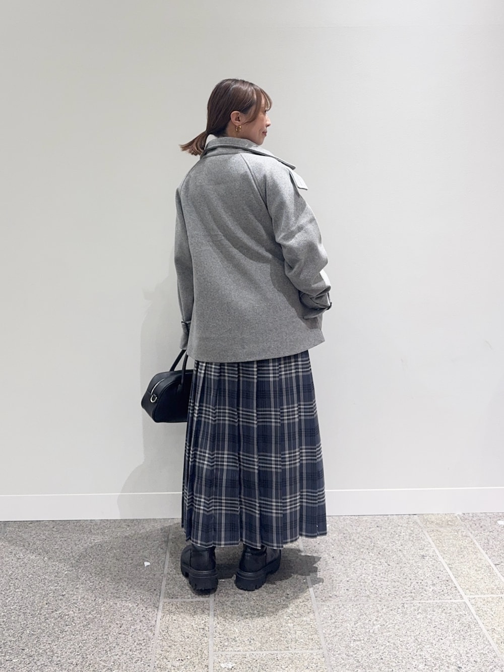 グレー系のその他アウター、ブラック系のニット/セーター、グレー系のスカートを着用したレディースの秋コーディネートの3枚目の写真