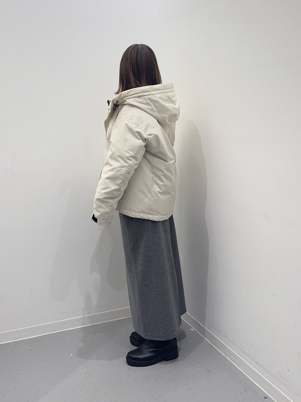 ホワイト系のダウンジャケット/コート、グレー系のニット/セーター、グレー系のスカートを着用したレディースの冬コーディネートの3枚目の写真