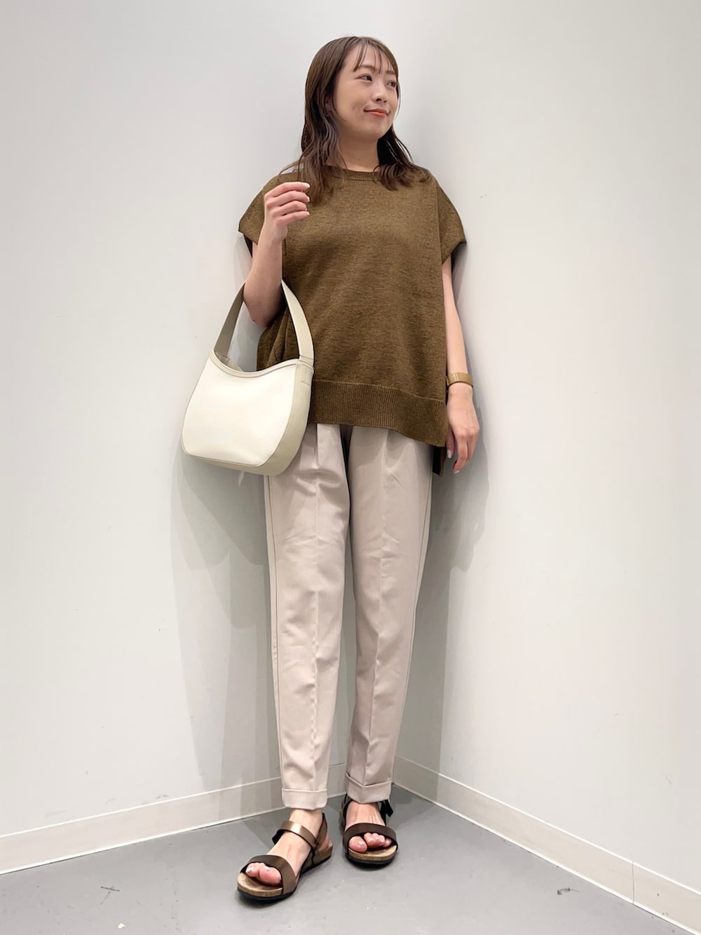 イエロー系のトップス、ベージュ系のその他パンツ、ブラウン系のサンダルを着用したレディースの夏コーディネートの2枚目の写真