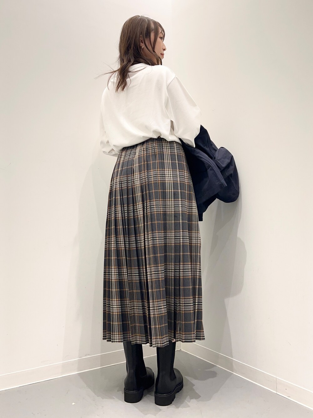 ホワイト系のTシャツ/カットソー、グレー系のスカート、ブルー系のダウンベストを着用したレディースの秋コーディネートの4枚目の写真