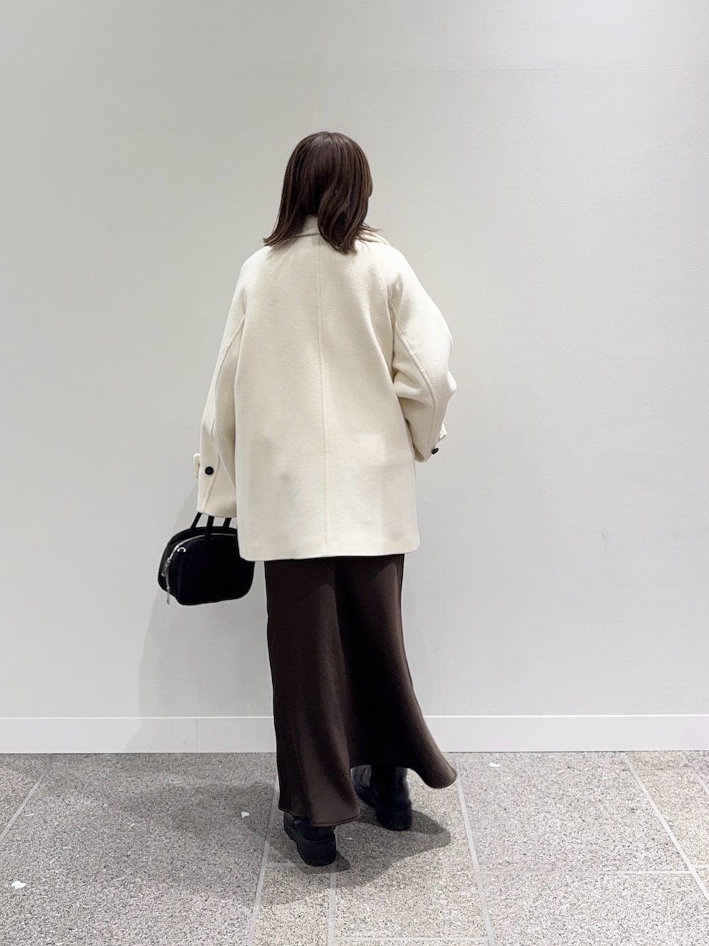 ホワイト系のピーコート、ホワイト系のニット/セーター、ブラック系のボストンバッグを着用したレディースの冬コーディネートの3枚目の写真