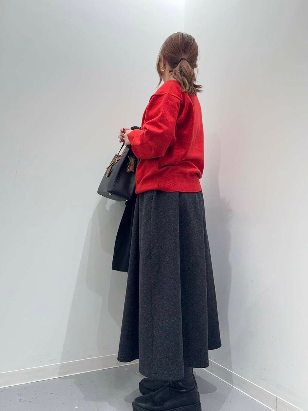 ブラック系のトートバッグ、ブラック系のブーツ、レッド系のニット/セーターを着用したレディースの冬コーディネートの6枚目の写真