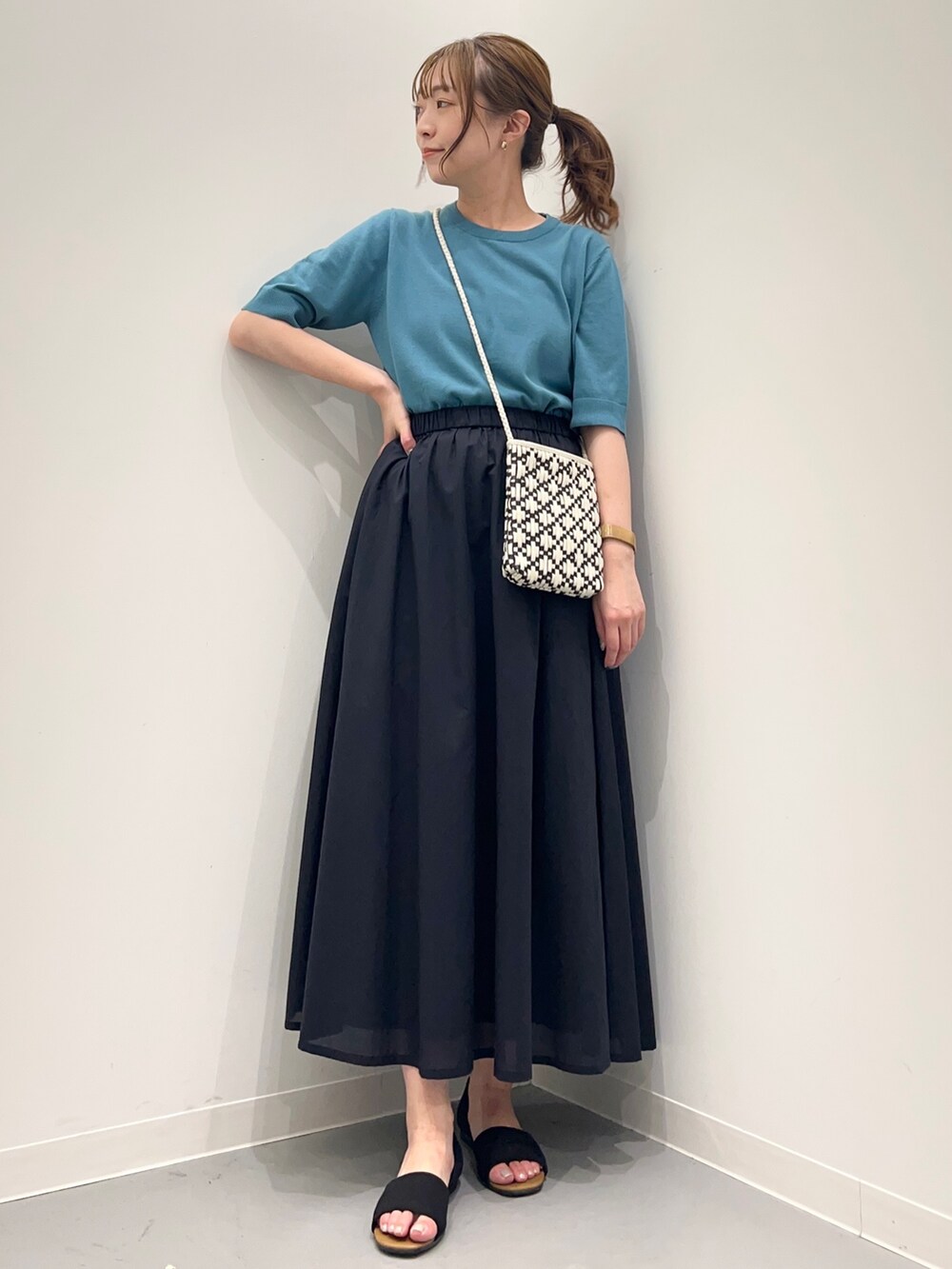 ブルー系のニット/セーター、ブルー系のスカート、ブラック系のサンダルを着用したレディースの春コーディネートの2枚目の写真