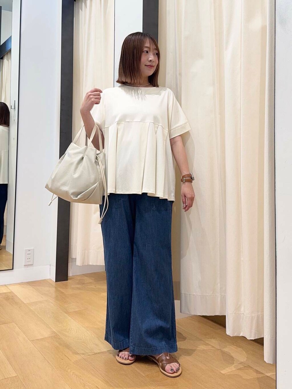 ブラウン系のサンダル、ブルー系のデニムパンツ、ホワイト系のショルダーバッグを着用したレディースの夏コーディネートの2枚目の写真