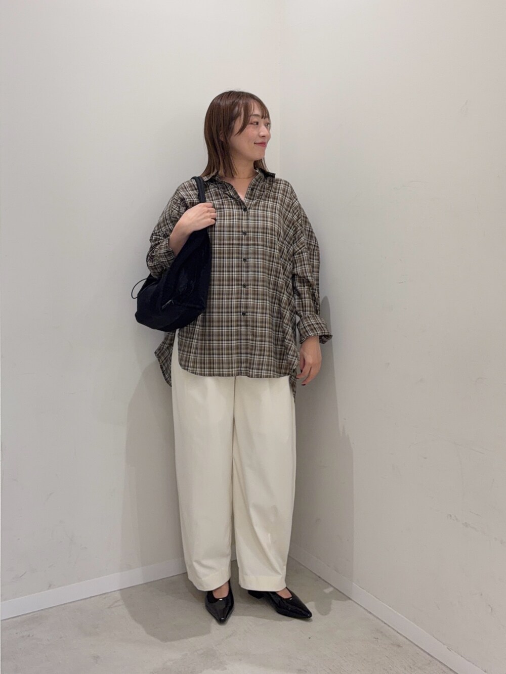 ブラウン系のシャツ/ブラウス、ホワイト系のその他パンツ、ブラック系のトートバッグを着用したレディースの秋コーディネートの2枚目の写真