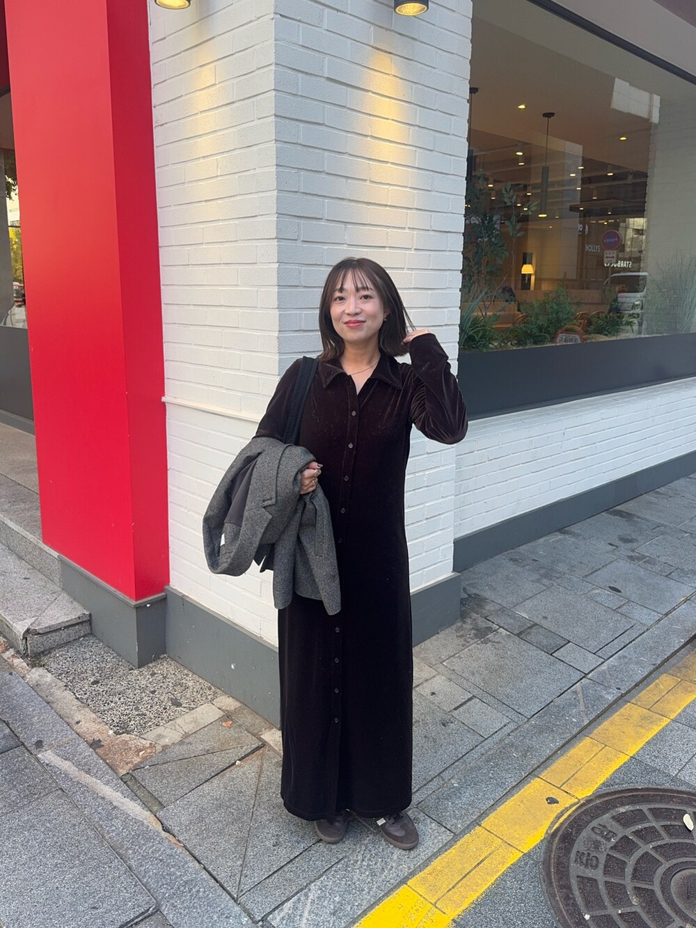 ブラウン系のワンピース、ブラウン系のスニーカー、ブラック系のショルダーバッグを着用したレディースの秋コーディネートの5枚目の写真