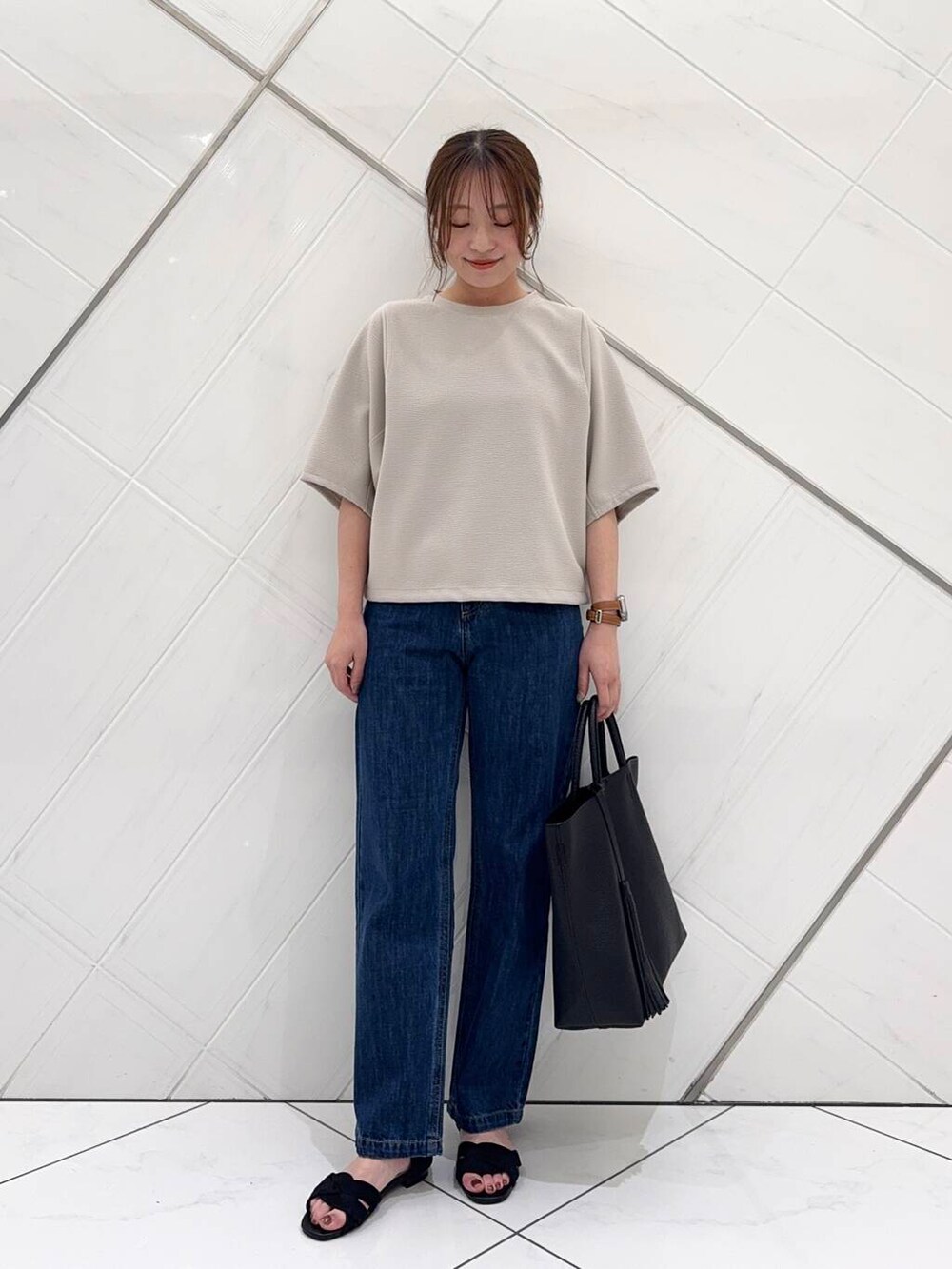 ブルー系のデニムパンツ、ブラック系のトートバッグ、ブラック系のサンダルを着用したレディースの春コーディネートの3枚目の写真