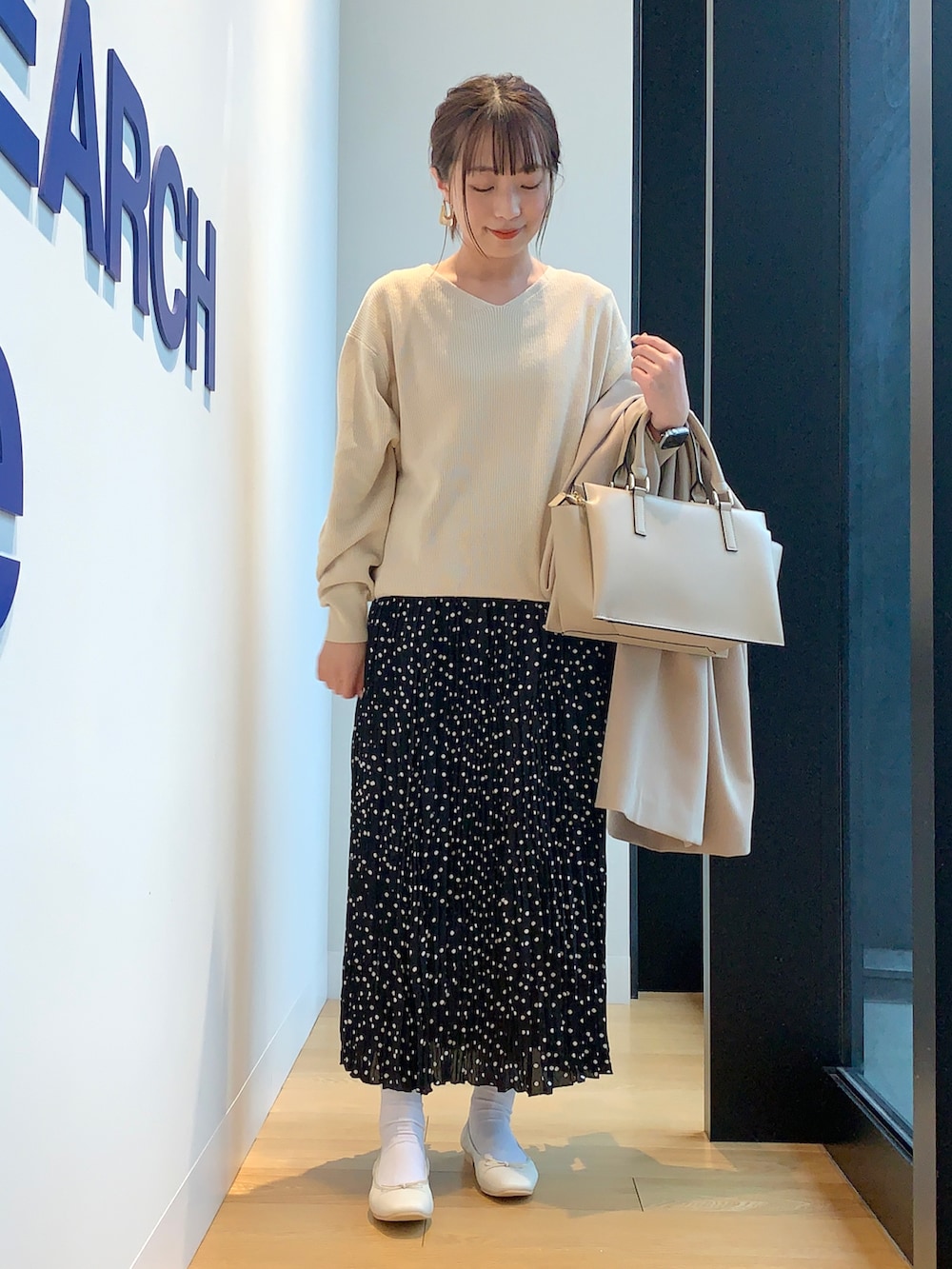 ホワイト系のニット/セーター、ブラック系のスカート、ベージュ系のその他アウターを着用したレディースの春コーディネートの3枚目の写真