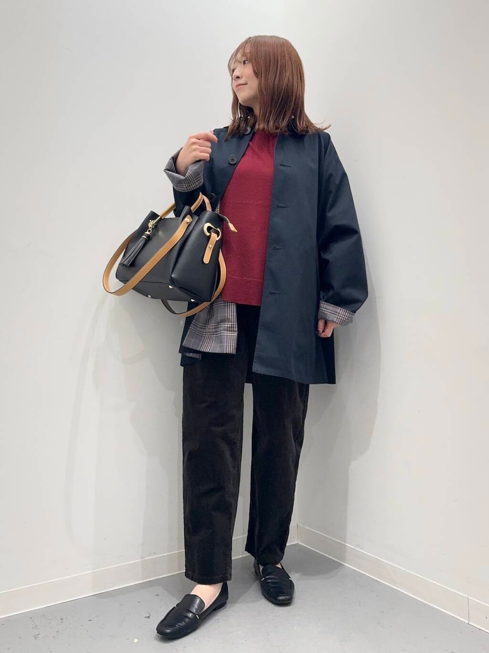 ブラック系のローファー、ブラック系のトートバッグ、ブルー系のステンカラーコートを着用したレディースの秋コーディネートの4枚目の写真