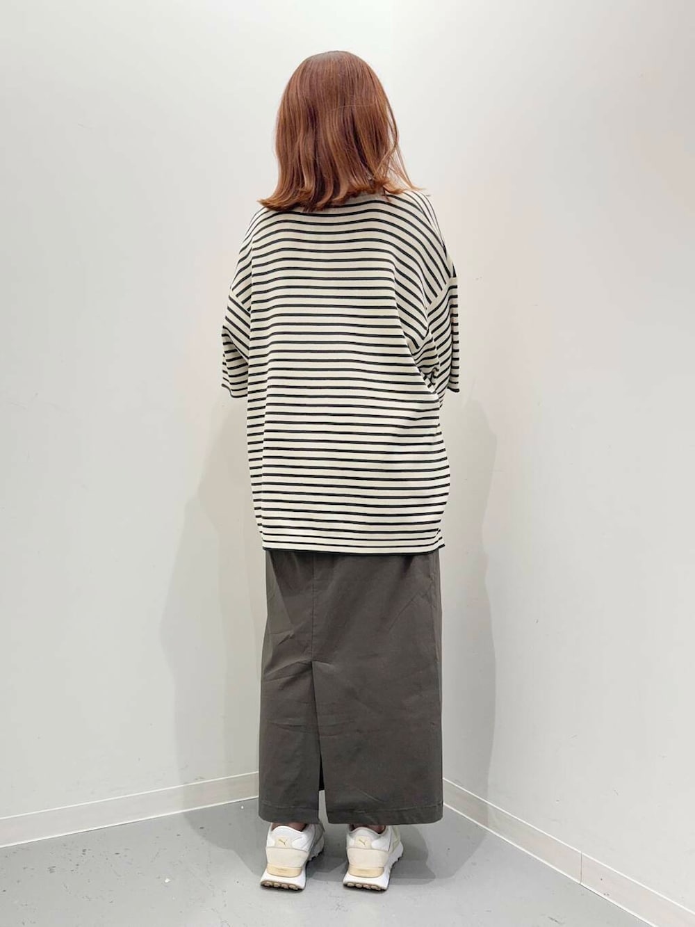 グリーン系のスカート、ゴールド系のハンドバッグ、ホワイト系のスニーカーを着用したレディースの夏コーディネートの4枚目の写真