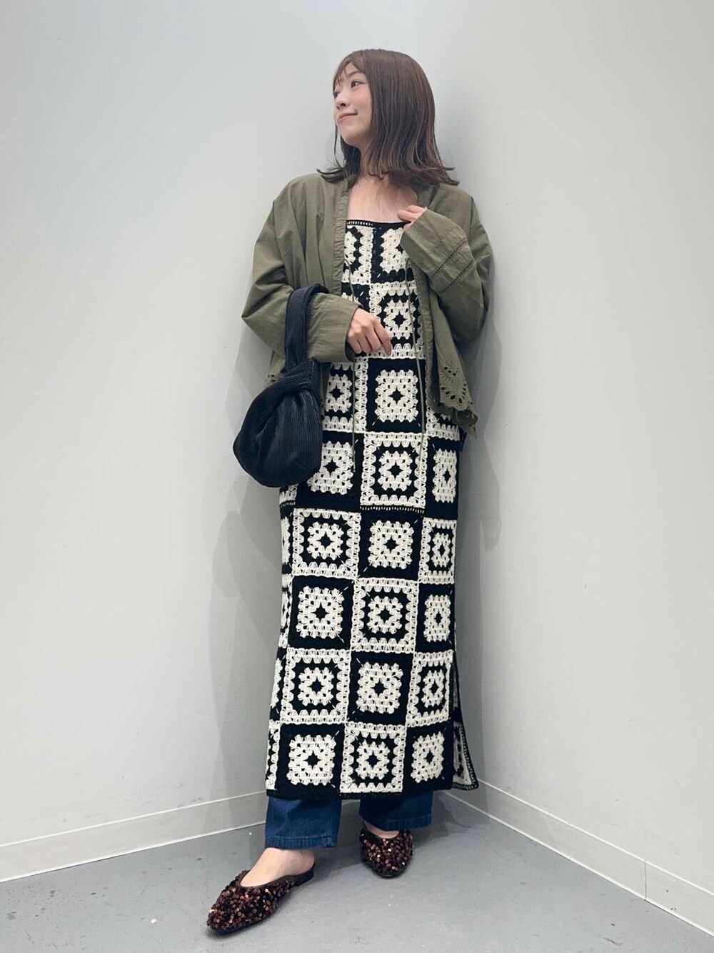 ブラック系のハンドバッグ、ブルー系のデニムパンツ、グリーン系のカーディガン/ボレロを着用したレディースの秋コーディネートの5枚目の写真