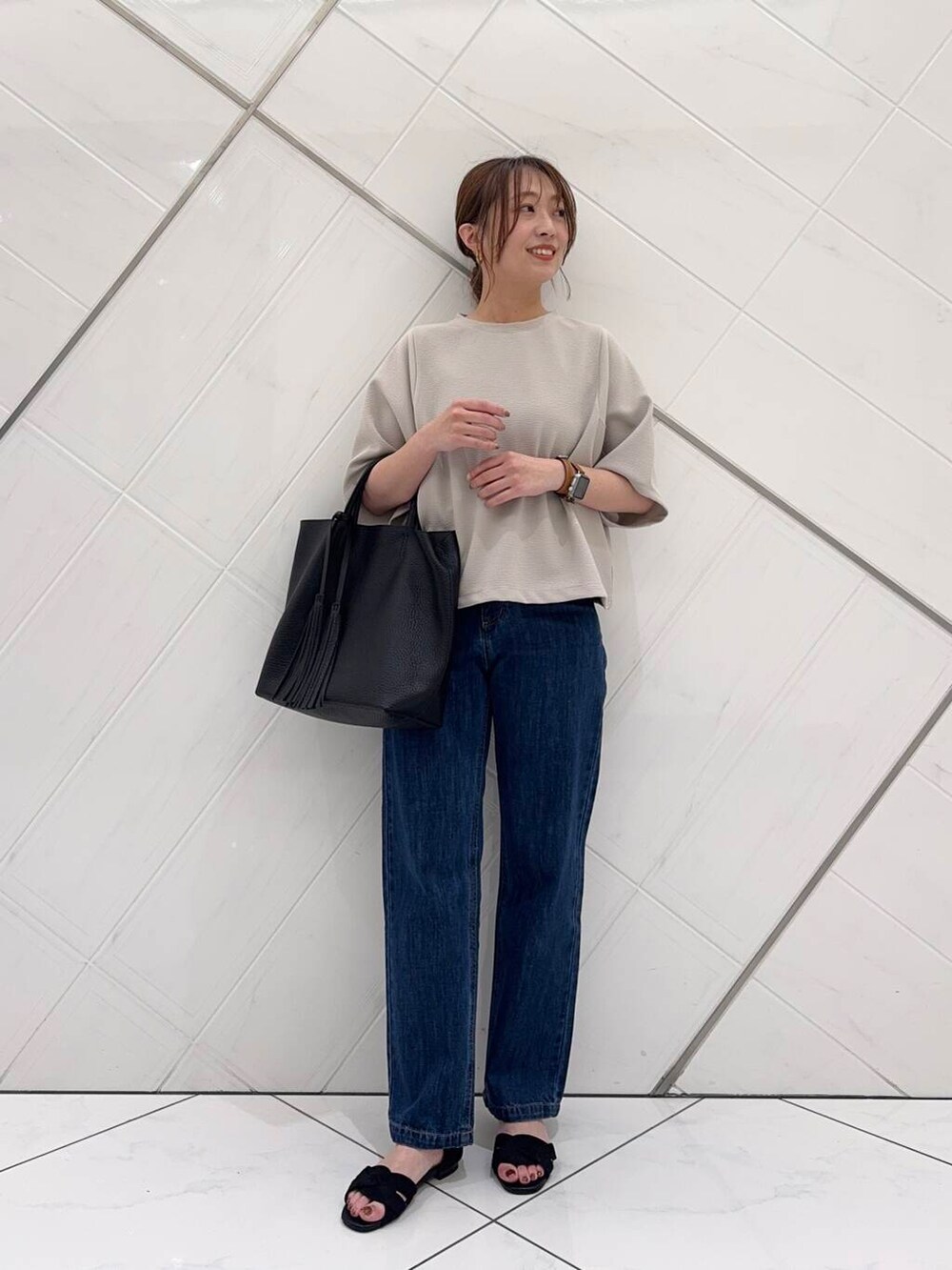 ブルー系のデニムパンツ、ブラック系のトートバッグ、ブラック系のサンダルを着用したレディースの春コーディネートの2枚目の写真