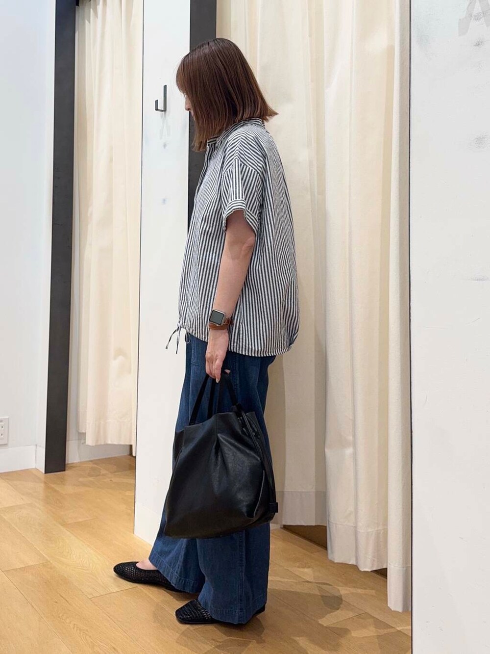 ブラック系のショルダーバッグ、ブルー系のデニムパンツ、ブラック系のバレエシューズを着用したレディースの夏コーディネートの3枚目の写真