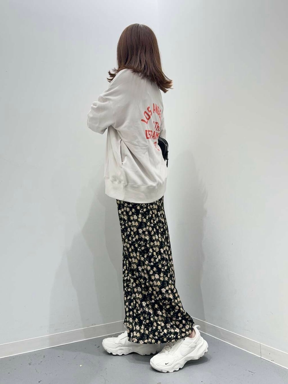 ホワイト系のスニーカー、ブラック系のボストンバッグ、ブラック系のスカートを着用したレディースの秋コーディネートの2枚目の写真