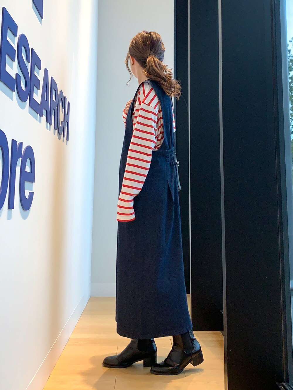 ブルー系のワンピース、レッド系のTシャツ/カットソー、ブラック系のブーツを着用したレディースの冬コーディネートの3枚目の写真