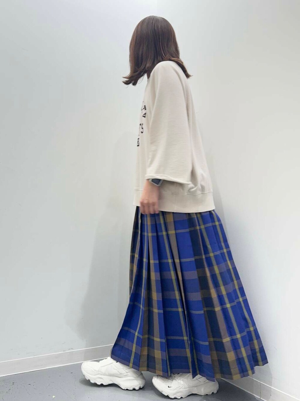 ベージュ系のTシャツ/カットソー、ブルー系のスカートを着用したレディースの秋コーディネートの2枚目の写真