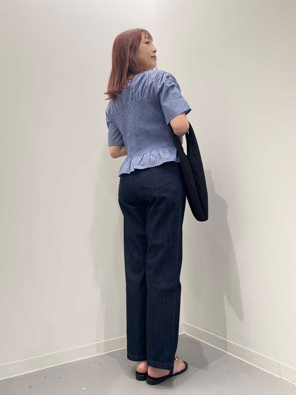 ブルー系のデニムパンツ、ブラック系のサンダル、ブラック系のトートバッグを着用したレディースの夏コーディネートの4枚目の写真
