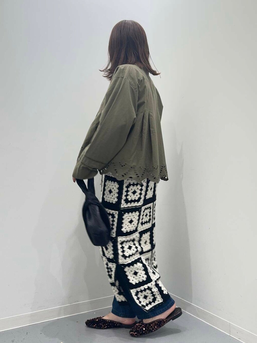 ブラック系のハンドバッグ、ブルー系のデニムパンツ、グリーン系のカーディガン/ボレロを着用したレディースの秋コーディネートの3枚目の写真