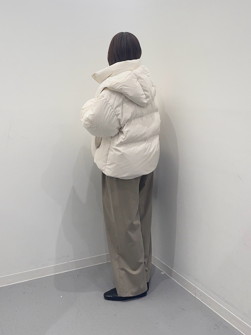 ホワイト系のダウンジャケット/コート、ベージュ系のその他パンツ、ブラック系のハンドバッグを着用したレディースの冬コーディネートの2枚目の写真