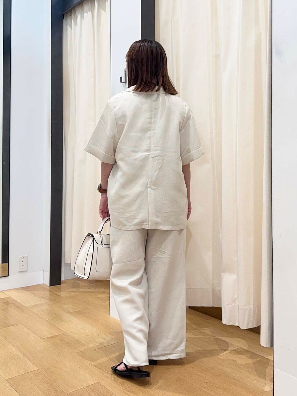 ホワイト系のハンドバッグ、ブラック系のサンダル、ホワイト系のTシャツ/カットソーを着用したレディースの夏コーディネートの4枚目の写真