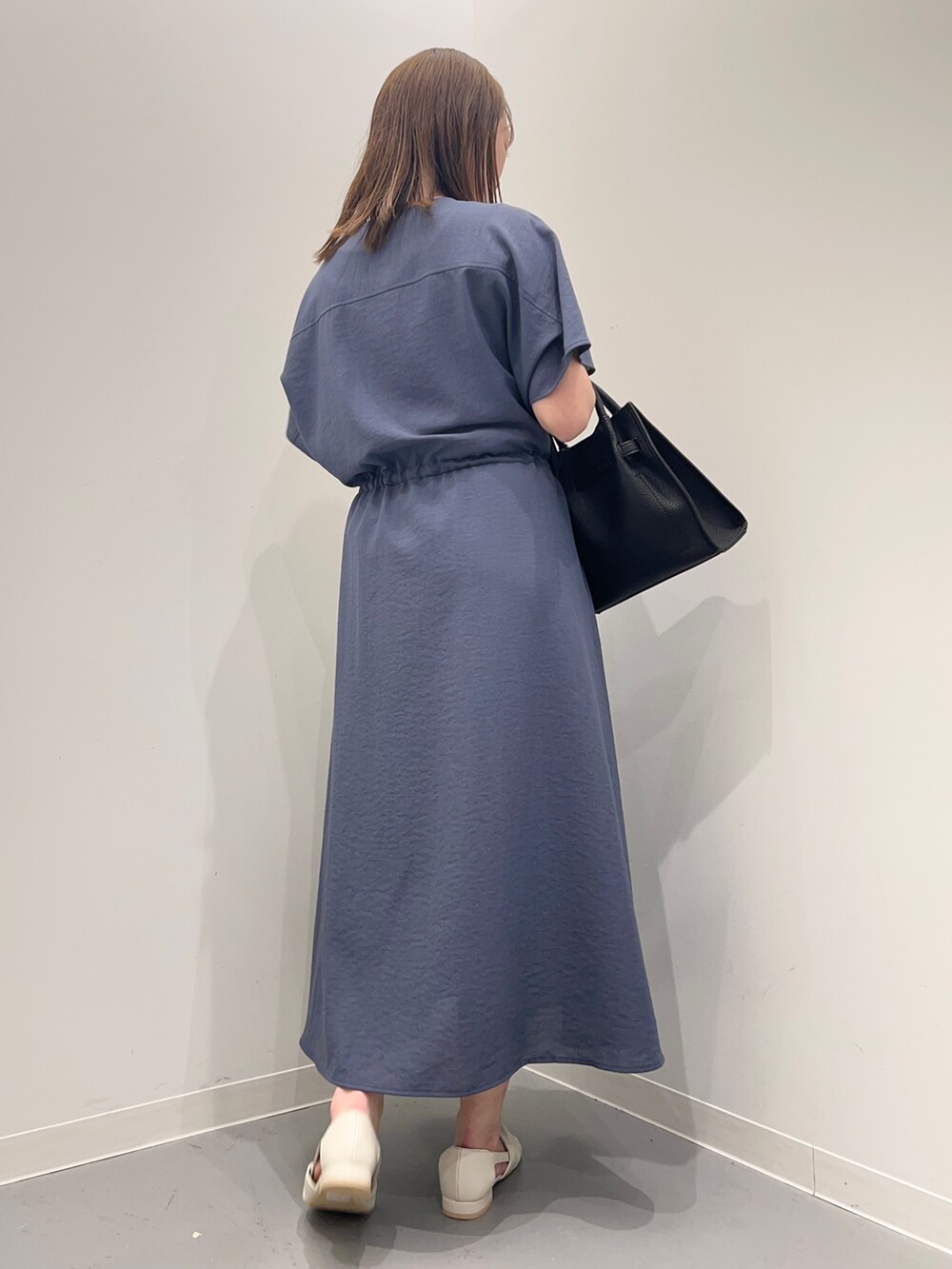 ブルー系のワンピース、ホワイト系のパンプス、ブラック系のトートバッグを着用したレディースの春コーディネートの4枚目の写真