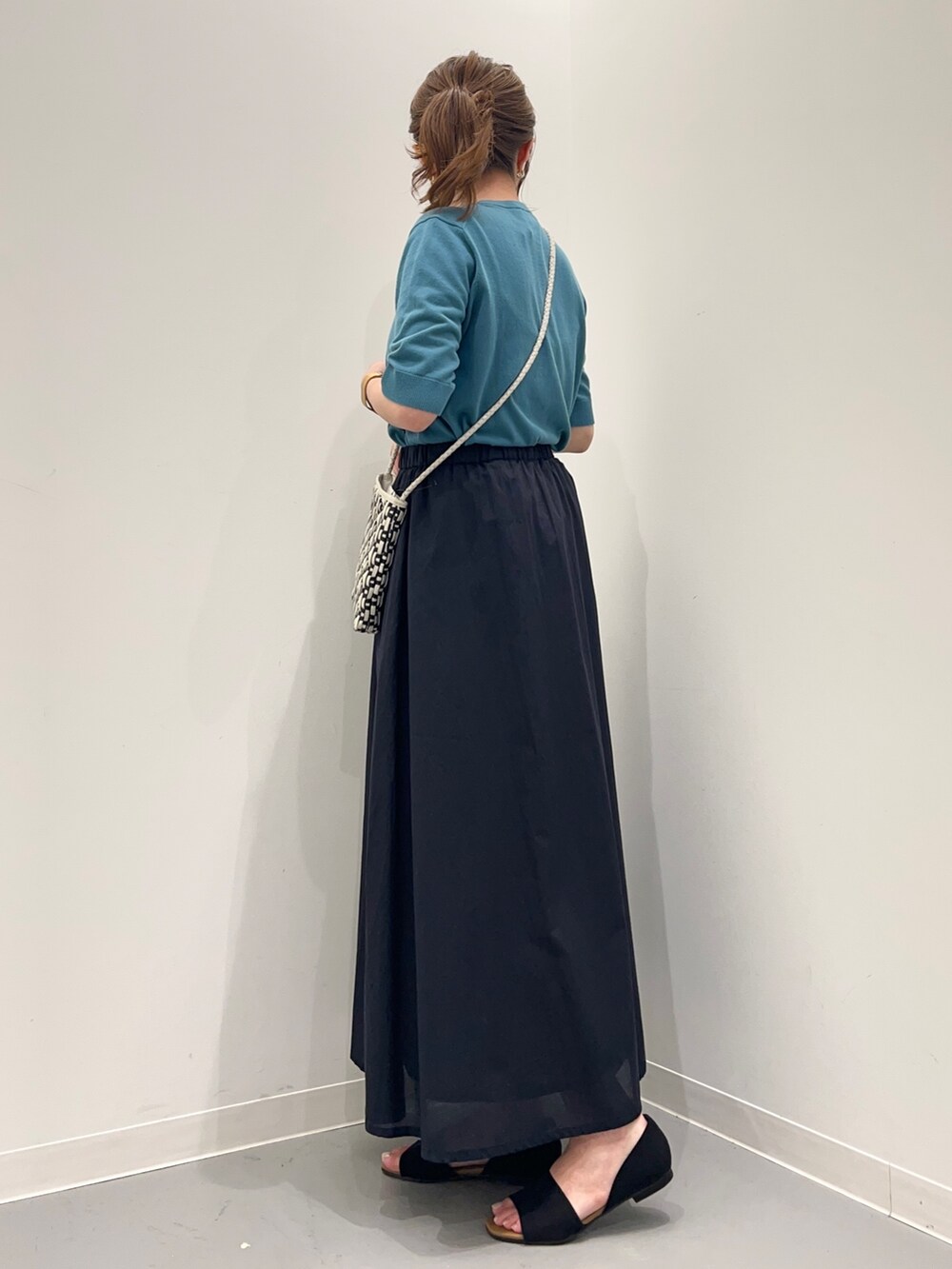 ブルー系のニット/セーター、ブルー系のスカート、ブラック系のサンダルを着用したレディースの春コーディネートの3枚目の写真