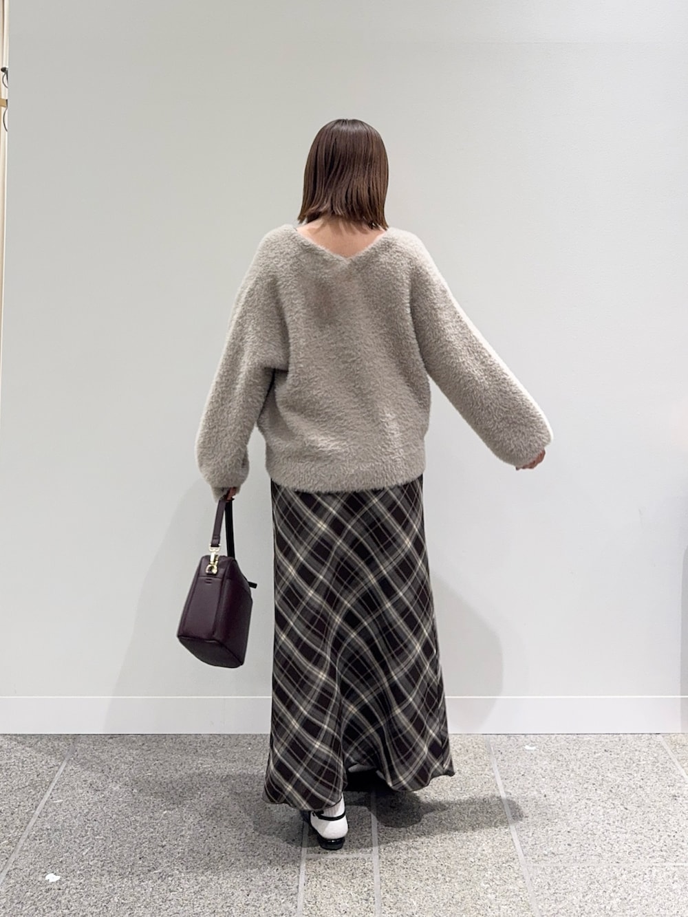 ベージュ系のカーディガン/ボレロ、ブラウン系のスカート、レッド系のショルダーバッグを着用したレディースの秋コーディネートの3枚目の写真