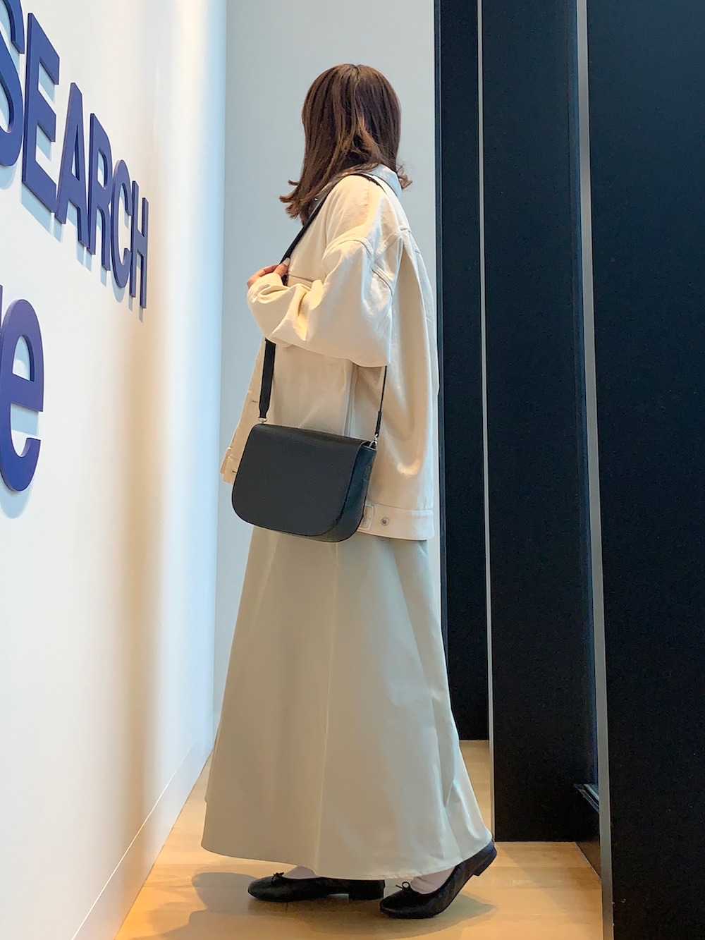 ベージュ系のカバーオール、ブルー系のニット/セーター、グリーン系のスカートを着用したレディースの春コーディネートの2枚目の写真