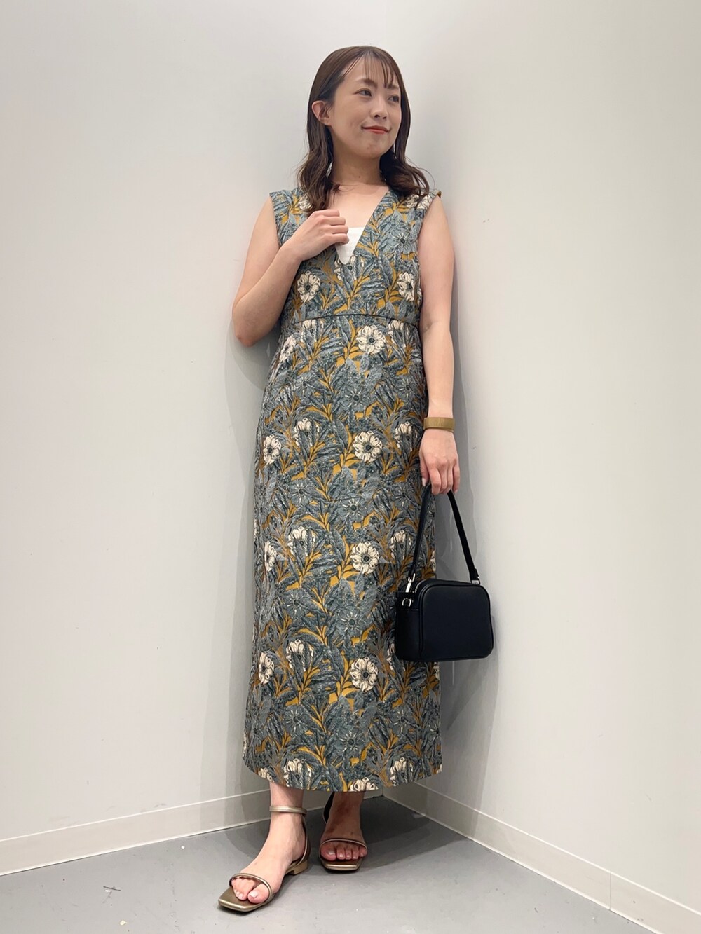 イエロー系のワンピース、ゴールド系のサンダル、ブラック系のショルダーバッグを着用したレディースの夏コーディネートの5枚目の写真