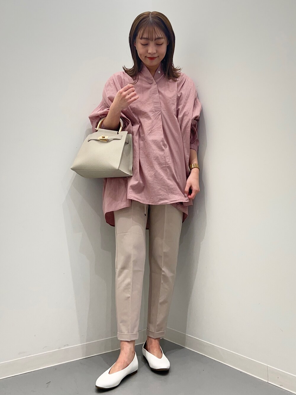 ピンク系のシャツ/ブラウス、ベージュ系のその他パンツ、ホワイト系のパンプスを着用したレディースの春コーディネートの2枚目の写真